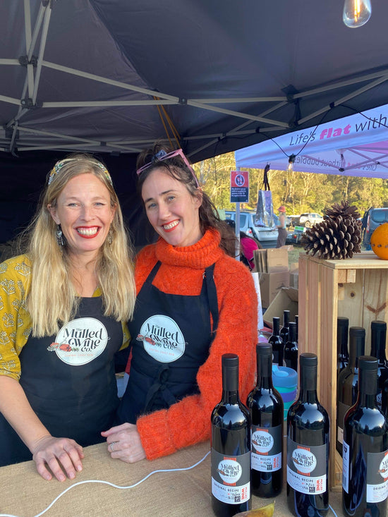 The Mulled Wine Co staff posing for a photo at their market stall dressed in aprons.