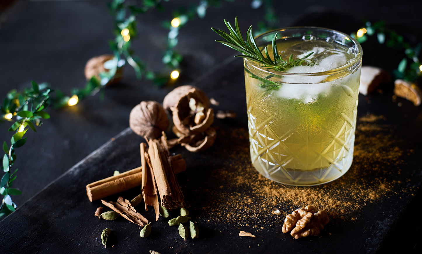 A refreshing-looking glass tumbler filled with chilled white mulled wine, ice and a rosemary sprig.